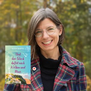 Portraitbild der Autorin Susa Bartel inklusive Cover-Bild ihres Buches "Und das Glück riecht nach Wolken und Meer". Susa Bartel hat halblange braune Haar und trägt eine dezente Brille.