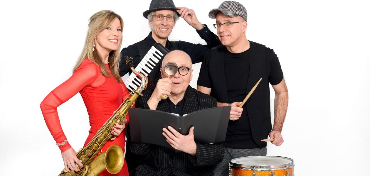 Das Bild zeigt Jo Jung und die Band Boogaloo. Es sind drei schwarzgekleidete Männer zu sehen und eine Frau in rotem Kleid. Die Band hat Instrumente in den Händen, Jo Jung ein Buch und eine Lupe.