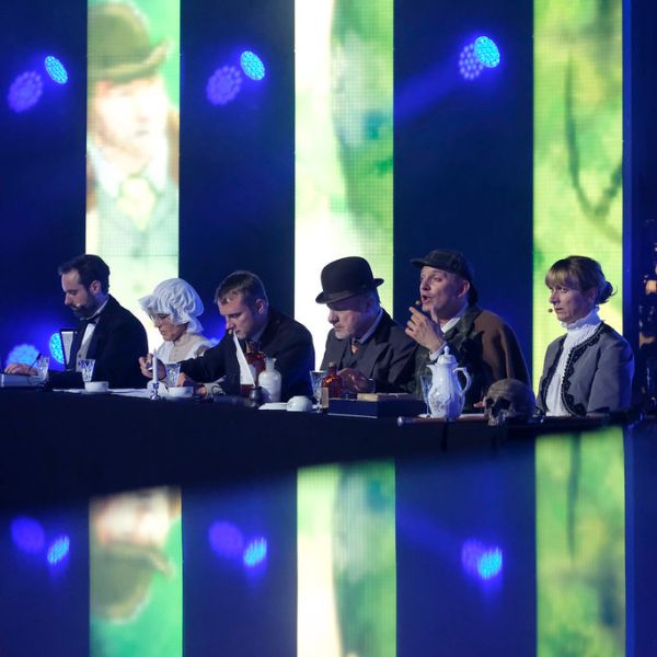 Das Ensemble des RadioLiveTheaters, verkleidet als Sherlock Holmes, vor beleuchtetem Hintergrund